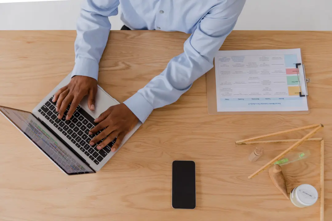 Overhead view of a person working on a laptop beside an order sheet.